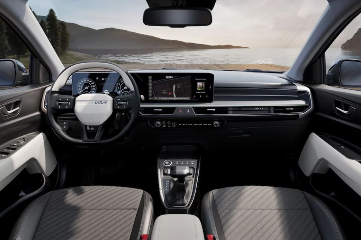 Volledig panoramisch interieur aanzicht van 2025 Kia Stonic met compleet dashboard, dubbele schermen, stuurwiel, stoelen met gewatteerd patroon en schilderachtig uitzicht door voorruit