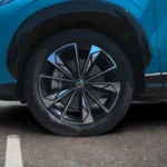 Detailopname van 2025 MG HS 19-inch lichtmetalen velg met diamant-geslepen spakendesign, MG merk naafkap en band zijwand op Arctic Blue voertuig