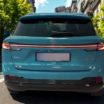 2025 MG HS Hybrid+ in Arctic Blue gefotografeerd van achteren op stadsstraat met stedelijke architectuur achtergrond, met volledige LED-achterlichten en moderne SUV-proporties