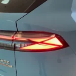 Close-up detailopname van 2025 MG HS achterlicht met verlichte LED-elementen en Hybrid+ badge op Arctic Blue lakwerk