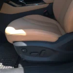 Close-up van de bestuurdersstoel van de 2025 MG HS Hybrid+ met elektrische verstelling, premium beige leereffect bekleding en ergonomische designdetails