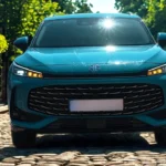 Frontaal vooraanzicht van 2025 MG HS Hybrid+ in Arctic Blue op kinderkopjes met verlichte LED-dagrijverlichting, MG-logo en grote voorgrille
