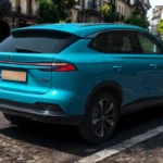 2025 MG HS Hybrid+ SUV in Arctic Blue rijdend op stadsstraat vanuit achter drie-kwart perspectief, met dynamische beweging en stedelijke omgeving