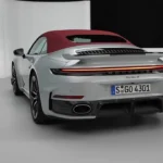 Zilveren 2025 Porsche 911 Turbo S Cabriolet vanuit achteraanzicht met rode stof cabriokap omhoog, met "Turbo S" badge, LED achterlichtstrip en vierkante uitlaatpijpen