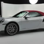 Zilveren 2025 Porsche 911 Turbo S Cabriolet zijaanzicht met rode cabriokap, met E-Hybrid badge op deur, meerspaaks lichtmetalen velgen en zij-luchtinlaten