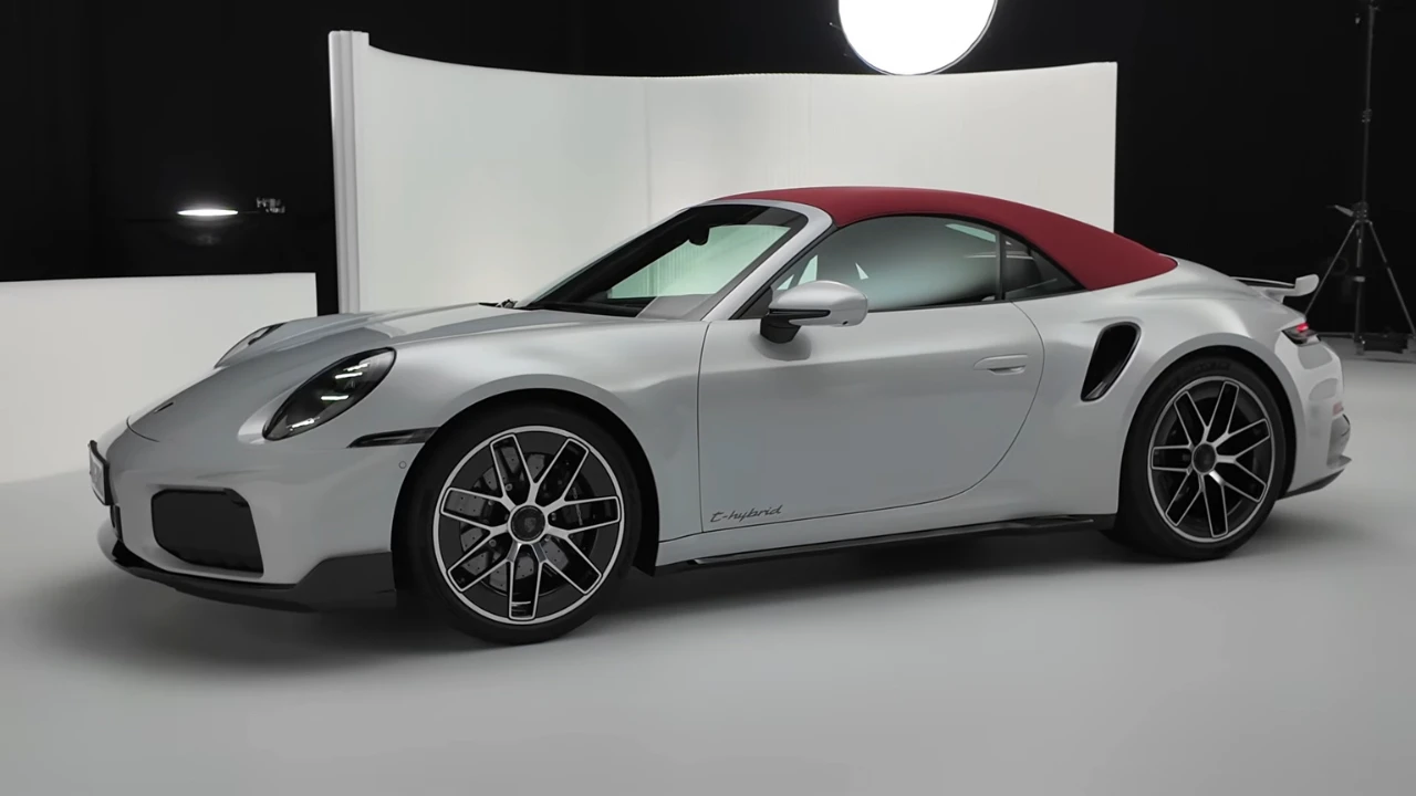 Zilveren 2025 Porsche 911 Turbo S Cabriolet zijaanzicht met rode cabriokap, met E-Hybrid badge op deur, meerspaaks lichtmetalen velgen en zij-luchtinlaten