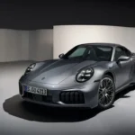 Metallic grijze 2025 Porsche 911 Turbo S Coupe vanuit voorste driekwart hoek in studio-omgeving, met brede voorbumper met grote luchtinlaten, LED koplampen en agressief aerodynamisch ontwerp