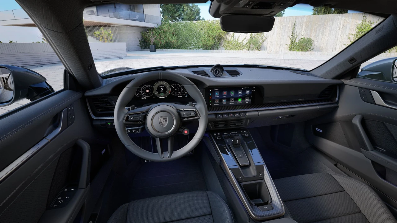 Interieur bestuurder aanzicht van 2025 Porsche 911 Turbo S met stuurwiel, instrumentencluster, centraal infotainment scherm en modern dashboard ontwerp met hybride systeem displays