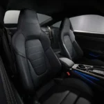 Detail van 2025 Porsche 911 Turbo S sportstoelen met Turbo S geëtste hoofdsteunen, premium leren bekleding en ergonomisch ontwerp met blauwe accent verlichting