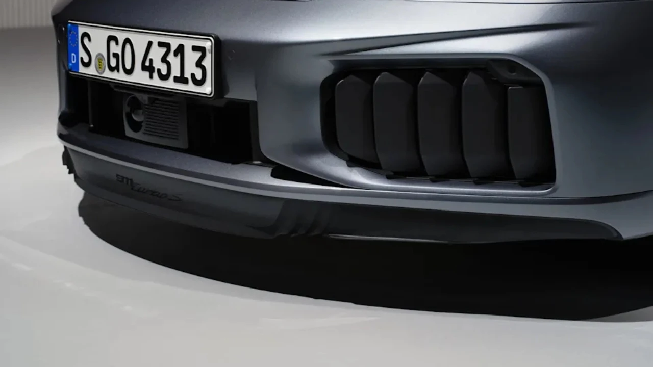 Close-up detail van 2025 Porsche 911 Turbo S voorbumper met grote rechthoekige luchtinlaat roosters met horizontale lamellen voor verbeterde motor en hybride systeem koeling