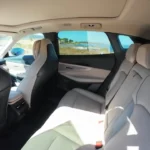 Ruime achterpassagiers gebied met de royale 963mm achter beenruimte door de 2,85m wielbasis, premium bekleding, voldoende hoofdruimte, en gezinsvriendelijk zitcomfort voor drie passagiers.