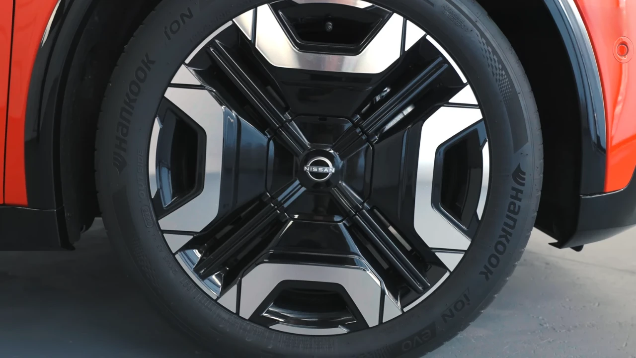 Close-up van 18-inch lichtmetalen velg op rode 2026 Nissan Micra met gedetailleerd spakenpatroon, Nissan-naafkap en band zijwand