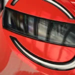 Close-up detail van ronde LED-koplamp op rode 2026 Nissan Micra met cirkelvormig lichtpatroon met geïntegreerde dagrijverlichting