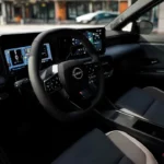 Zij-interieurzicht van 2026 Nissan Micra met modern dashboard, dubbele schermen, sportieve stoelen en hedendaags cabineontwerp