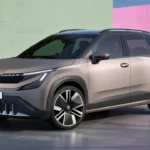 Voor-driekwart aanzicht van de 2026 Skoda Epiq elektrische SUV in champagne metallic kleur met Modern Solid design, LED-koplampen, zwarte grille met verticale lamellen en grote lichtmetalen velgen op een gradiënt studio-achtergrond