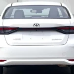 Witte 2026 Toyota Corolla sedan achteraanzicht met nieuw verbonden achterlicht design met LED strip over kofferbak, Corolla logo, en verfijnde bumper styling die de praktische sedan proporties behoudt