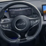 Gedetailleerd zicht op het moderne stuurwiel van de BYD Seal 6 DM-i met geïntegreerde bedieningselementen en de 8,8-inch LCD digitale instrumentencluster die hybridesysteeminformatie en voertuiggegevens toont.