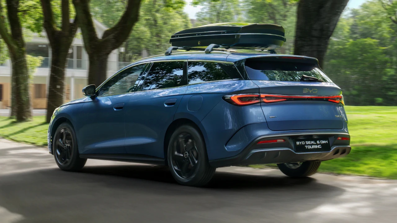 Toont de gezinsgerichte veelzijdigheid van de BYD Seal 6 DM-i Touring, uitgerust met dakkoffer voor extra opslag, perfect voor Nederlandse gezinsvakanties met 500-1.535 liter totale capaciteit.