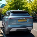 Lichtblauwe Jaecoo 7 PHEV SUV geparkeerd op Europese straat met bomen, achterkant driekwart aanzicht en modern design