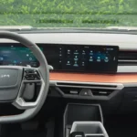 Breed zicht op 2025 KGM Torres Hybrid dashboard met dubbele 12,3-inch displays die panoramisch scherm vormen, stuurwiel, horizontale oranje afgezette ventilatieroosters en schoon minimalistisch interieurontwerp