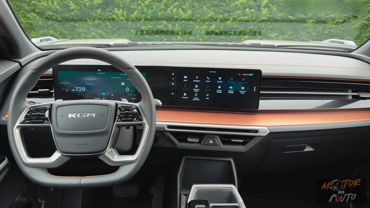 Breed zicht op 2025 KGM Torres Hybrid dashboard met dubbele 12,3-inch displays die panoramisch scherm vormen, stuurwiel, horizontale oranje afgezette ventilatieroosters en schoon minimalistisch interieurontwerp