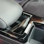 Bovenaanzicht van 2025 KGM Torres Hybrid middenconsole met draadloze oplaadplaat met rubber grip oppervlak, verchroomde bekerhouders en opbergvakken met oranje accentverlichting