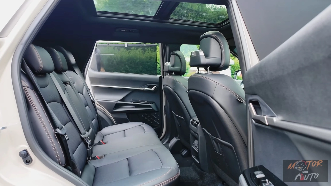 Interieurzicht vanuit achterdeur van 2025 KGM Torres Hybrid met ruime achterbank met grijze lederen stoelen, royale beenruimte, panoramisch schuifdak en zicht door naar voorstoelen met natuurlijke verlichting