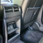 Detailopname van 2025 KGM Torres Hybrid achter middenconsole met twee USB-C oplaadpoorten gemonteerd onder klimaatroosters met grijs en zwart interieur afwerking