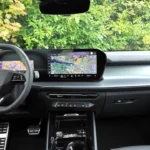 Breedhoek interieurzicht van 2026 Audi Q3 cabine met zwarte sportstoelen, gebogen digitaal dashboarddisplay, panoramisch schuifdak, middenconsole met bekerhouders en draadloos opladen, en premium microvezelige afwerkingsdetails