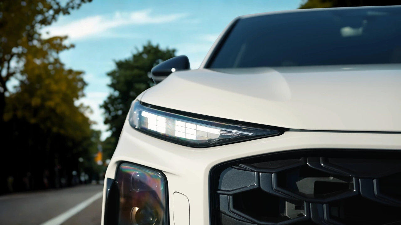 Close-up detail van 2026 Audi Q3 slanke LED-koplamp unit met micro-LED matrix technologie met meerdere LED-segmenten, geïntegreerde richtingaanwijzer en zwarte behuizing tegen wit carrosseriepaneel