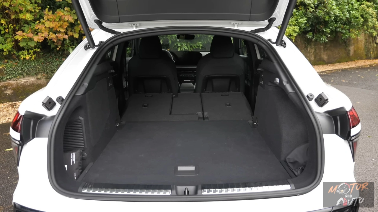 2026 Audi Q3 Sportback laadruimte met achterstoelen plat gevouwen met maximale 1.386L capaciteit, continue vlakke laadvloer, zwart tapijt oppervlak, zijopbergruimte zakken en lading tie-down punten