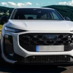 Direct vooraanzicht van de 2026 Audi Q3 op schilderachtige plattelandsweg met de imposante uitstraling van de Singleframe grille, gesplitst LED-verlichtingsontwerp op twee niveaus, brede stance met zichtbare wielkasten, onderste zwarte luchtinlaten en moderne compacte SUV-proporties tegen bergachtergrond.