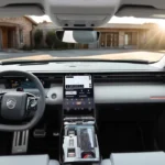 Interieur dashboardweergave van 2026 Citroën C5 Aircross met 13-inch centraal touchscreen, digitaal instrumentenpaneel, met leer bekleed stuurwiel, lichtgrijze en zwarte bekleding, en panoramisch uitzicht op woonwijk