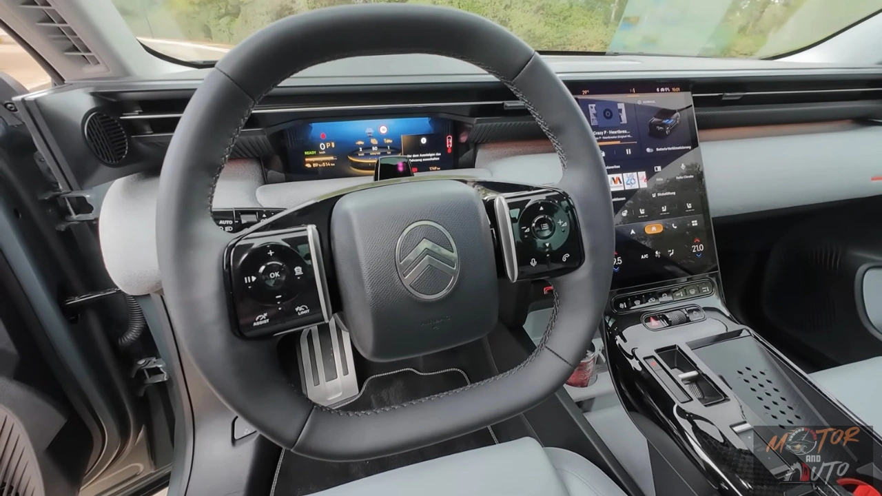 2026 Citroën C5 Aircross met leer bekleed stuurwiel met chromen accenten, knopbediening aan beide zijden, Citroën logo in het midden, en digitaal instrumentenpaneel zichtbaar erachter met navigatie display