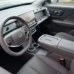 Voorste interieur cabine van de 2026 Leapmotor B10 met lichtgrijze eco-lederen stoelen en ruim dashboard layout