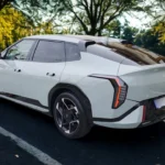 De 2026 Kia EV4 in Snow White Pearl toont zijn kenmerkende fastback-profiel en verbonden LED-achterlichten in een natuurlijke omgeving