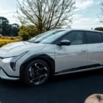 De 2026 Kia EV4 Fastback in Snow White Pearl presenteert zijn moderne elektrische ontwerp met onderscheidende LED-koplampen in een parkeergebied