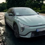 De 2026 Kia EV4 Fastback in Snow White Pearl toont zijn futuristisch frontontwerp met verticale LED-koplampen op een natte weg