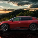 De 2026 Kia EV4 GT-Line in Magma Red toont zijn elegante fastback silhouet tegen een schilderachtige bergachtergrond tijdens het gouden uur