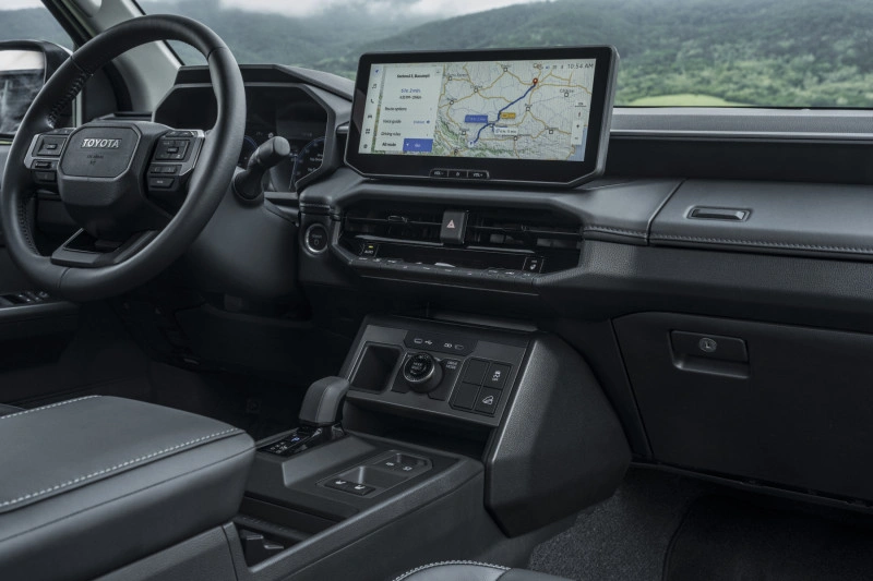 Passagierszijde van het dashboard van de 2026 Toyota Hilux BEV met de shift-by-wire middenconsole en 12,3-inch scherm.