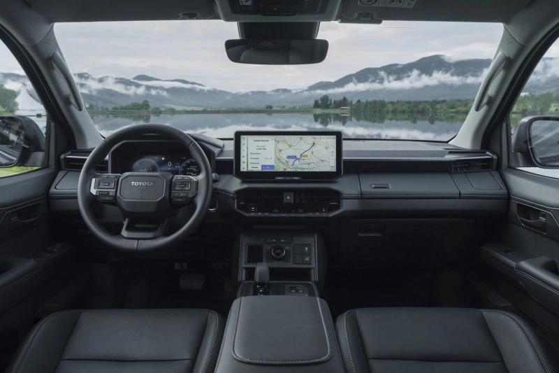 Dashboard-interieur van de 2026 Toyota Hilux BEV met 12,3-inch centraal touchscreen, digitaal instrumentarium en lederen stoelen.