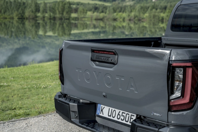 Achterklep van de 2026 Toyota Hilux BEV in Ash Grey met gestanste TOYOTA-letters, HILUX-lichtbalk en Duitse kentekenplaat.