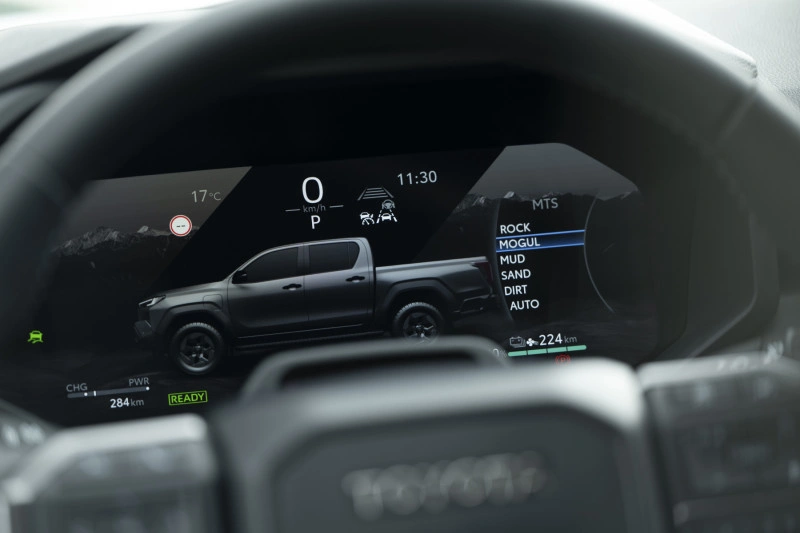 12,3-inch digitaal instrumentarium van de 2026 Toyota Hilux BEV met Multi-Terrain Select-modi en Mogul gemarkeerd.