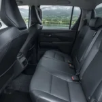 Achterbank van de 2026 Toyota Hilux BEV Double Cab in zwart leder met uitzicht op een meer.