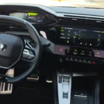 Interieur van de 2026 Peugeot 408 GT met stuur en klimaatmenu op het scherm.