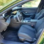 Voorstoelen van de 2026 Peugeot 408 GT door de open bestuurdersdeur.