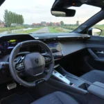 Dashboard en stuurwiel van de 2026 Peugeot 408 GT vanuit de bestuurdersdeur.