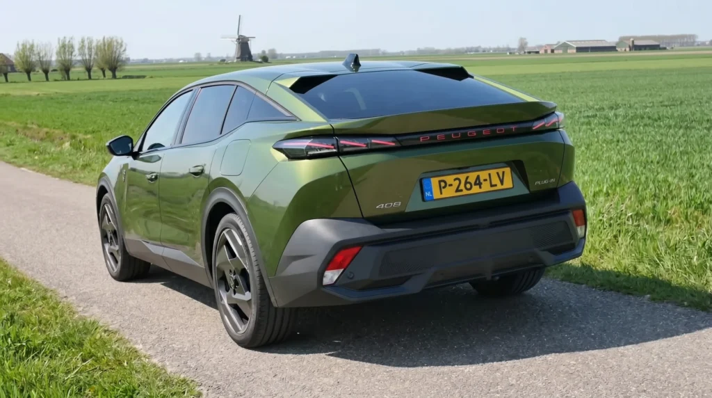 Schuin achteraanzicht van de groene 2026 Peugeot 408 Plug-in Hybrid bij een weiland.