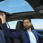 Bestuurder in de 2026 Peugeot 408 raakt het open panoramadak aan.