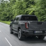 Achteraanzicht driekwart van de wegrijdende 2026 Toyota Hilux BEV met gestanste TOYOTA-achterklep.